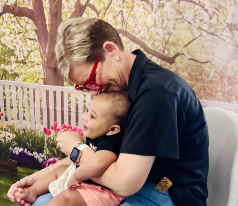 A caregiver holding a smiling baby in her lap